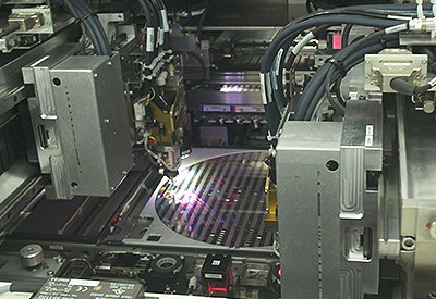 Silicon wafer being probed by machine in fab