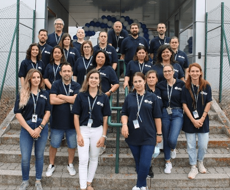 Group photo of smiling Amkor Portugal employees standing on steps