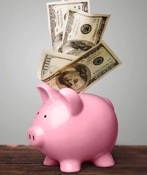 Image of pink piggy bank with dollars falling into it